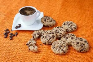 Chocolat puce biscuits et tasse de café coup sur jute coloré chiffon. photo