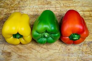 poivrons dans Trois couleurs sur une cuisine planche à pain. en train de préparer des légumes pour une en bonne santé salade. photo