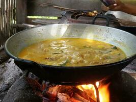 le processus de cuisine rendang ou du boeuf et poulet curry en utilisant le traditionnel méthode, cuisine en utilisant bois de chauffage photo