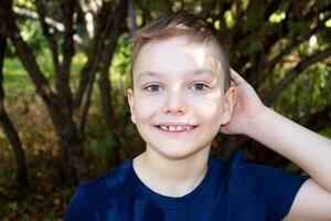 portrait de une 9 année vieux blond garçon dans un l'automne parc. Beau caucasien garçon avec gros yeux regards dans le caméra. photo