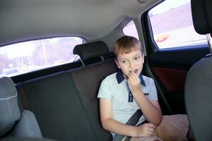 le garçon est portant une siège ceinture séance dans le retour siège de le auto. photo