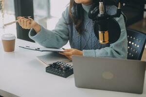 femme enregistrant un podcast sur son ordinateur portable avec un casque et un microscope. podcasteuse réalisant un podcast audio depuis son home studio. photo