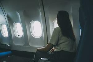 silhouette de femme regards en dehors le fenêtre de un en volant avion. passager sur le avion repos à côté de le la fenêtre. photo