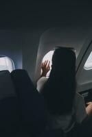 silhouette de femme regards en dehors le fenêtre de un en volant avion. passager sur le avion repos à côté de le la fenêtre. photo