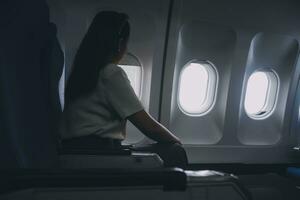 silhouette de femme regards en dehors le fenêtre de un en volant avion. passager sur le avion repos à côté de le la fenêtre. photo