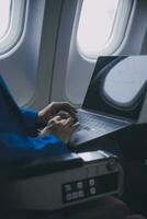 en utilisant mobile et ordinateur portable, réfléchi asiatique gens femelle la personne à bord, avion fenêtre, à la perfection Capturer le anticipation et excitation de vacances Voyage. Chinois, Japonais personnes. photo