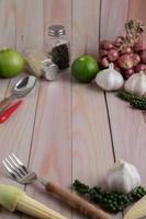 fourchette, bébé maïs, ail, poivre frais, citron vert et oignon rouge sur un plancher de bois blanc.