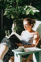 femme lisant un livre allongée sur une chaise pendant une journée ensoleillée, espace de copie, concepts de détente et de passe-temps, réseau social