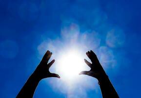 silhouette de mains contre Soleil et bleu ciel Contexte. mains sont élevé en haut à le Soleil photo