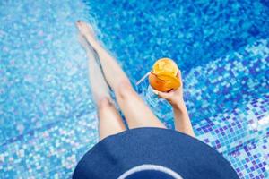 femme au chapeau bleu se détendre au bord de la piscine avec un cocktail photo