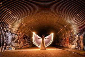 femme posant la lumière peinte avec des ailes dans un tunnel d'égout photo