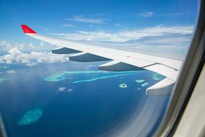 vue de dessus des îles maldives depuis le vol avec fenêtre d'avion. destination de vacances de luxe vue à travers la fenêtre d'un avion. incroyable paysage et paysage marin de l'île des maldives. concept de voyage exotique photo