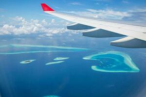 vue de dessus des îles maldives depuis le vol avec fenêtre d'avion. destination de vacances de luxe vue à travers la fenêtre d'un avion. incroyable paysage et paysage marin de l'île des maldives. concept de voyage exotique photo