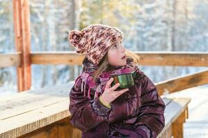 mignonne fille dans hiver dans glacial temps les boissons chaud thé de une thermos photo