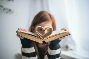 une fille est en portant une livre. en forme de coeur pages. en lisant, connaissance, apprentissage photo