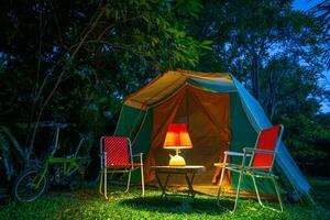 ancien cabine tente, antique pétrole lampe sur une en bois table avec rétro chaises. à nuit dans le forêt photo