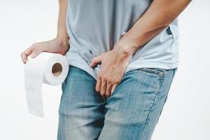 jeune homme tenant son entrejambe et son papier de soie souffrant de diarrhée, d'incontinence, de prostatite, de maladie vénérienne. concept de soins de santé. photo