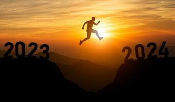 silhouette homme sauter content Nouveau année 2024 concept, homme sauter plus de barrière falaise et Succès de 2023 falaise à 2024 falaise avec le coucher du soleil Contexte. content Nouveau année pour la toile bannière et publicité. photo