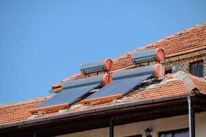 solaire panneaux et barils pour chauffage l'eau sur toit de le maison avec argile carrelage. photo