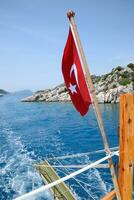 dinde drapeau à le arrière de une plaisir yacht. vue de méditerranéen côte photo