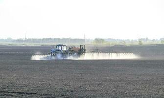 le tracteur pulvérisé herbicides sur le champ. chimie dans agricu photo