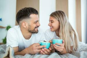 Jeune marié couple dans l'amour ayant café dans leur lit. bien Matin. en bonne santé petit déjeuner dans lit. Jeune magnifique l'amour couple est ayant café dans lit. photo