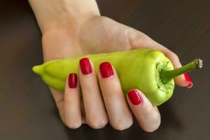 magnifique femelle main avec une rouge ongles en portant vert poivre. photo