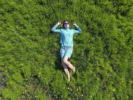 le fille mensonges dans une turquoise robe sur le pelouse. magnifique fille mensonge vers le bas de herbe photo