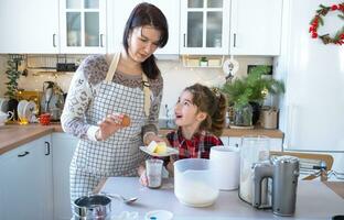 maman et fille dans le blanc cuisine sont en train de préparer biscuits, ajouter ingrédients. famille jour, préparation pour le vacances Noël, apprendre à cuisinier délicieux des pâtisseries, Couper formes en dehors de pâte avec moules photo