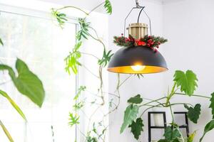 noir rétro métal grenier style abat-jour avec Noël décor et beaucoup intérieur les plantes sur une fenêtre dans une blanc intérieur. Nouveau année, confort à Accueil photo