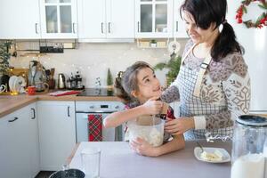 maman et fille dans le blanc cuisine sont en train de préparer biscuits, ajouter ingrédients. famille jour, préparation pour le vacances Noël, apprendre à cuisinier délicieux des pâtisseries, Couper formes en dehors de pâte avec moules photo