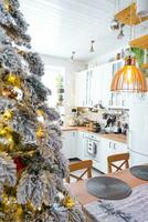 de fête Noël décor dans blanc cuisine, moderne rustique intérieur avec une neigeux Noël arbre et Fée lumières. Nouveau année, Noël humeur, confortable maison. le général plan photo