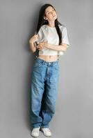 plein longueur portrait de une Jeune fille dans une blanc T-shirt et jeans. photo