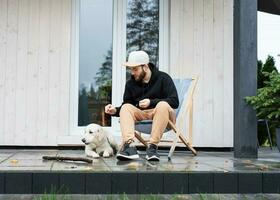 une Jeune homme repose près le sien pays maison avec une chien. photo