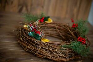 Noël couronne sur une en bois Contexte. Noël couronne fabriqué de brindilles, baies et des oranges. photo