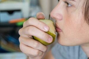 portrait de une adolescent garçon en mangeant une poire. fermer photo