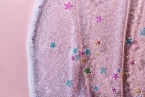 étoiles briller confettis sur beauté gel rose Contexte. brillant surligneur texture avec brosse coups photo