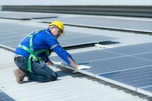 tous les deux de techniciens est installation solaire panneaux sur le toit de le entrepôt à changement solaire énergie dans électrique énergie pour utilisation dans des usines. photo