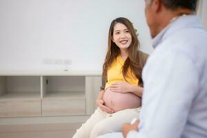 asiatique Enceinte femme visite gynécologue médecin à médical clinique pour grossesse consultant. médecin examiner Enceinte ventre pour bébé et mère soins de santé vérifier en haut. photo