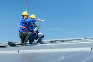 tous les deux de techniciens est installation solaire panneaux sur le toit de le entrepôt à changement solaire énergie dans électrique énergie pour utilisation dans des usines. photo