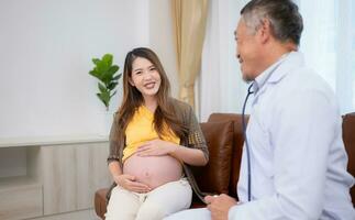 asiatique Enceinte femme visite gynécologue médecin à médical clinique pour grossesse consultant. médecin examiner Enceinte ventre pour bébé et mère soins de santé vérifier en haut. photo