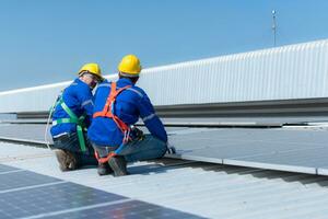 tous les deux de techniciens est installation solaire panneaux sur le toit de le entrepôt à changement solaire énergie dans électrique énergie pour utilisation dans des usines. photo