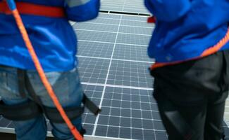 tous les deux de techniciens est installation solaire panneaux sur le toit de le entrepôt à changement solaire énergie dans électrique énergie pour utilisation dans des usines. photo