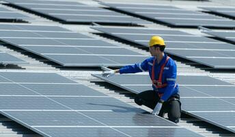 une technicien est installation solaire panneaux sur le toit de le entrepôt à changement solaire énergie dans électrique énergie pour utilisation dans des usines. photo