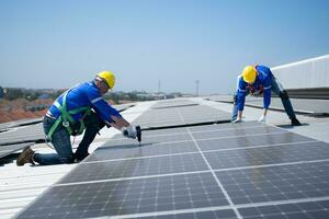 tous les deux de techniciens est installation solaire panneaux sur le toit de le entrepôt à changement solaire énergie dans électrique énergie pour utilisation dans des usines. photo