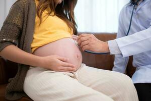 asiatique Enceinte femme visite gynécologue médecin à médical clinique pour grossesse consultant. médecin examiner Enceinte ventre pour bébé et mère soins de santé vérifier en haut. photo