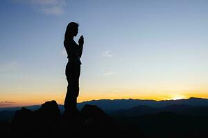 silhouette de la jeune fille a prié dans les montagnes pour penser à un dieu aimant, nous louons dieu. photo