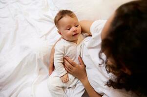 vue de au dessus de caucasien enfant, adorable nouveau née bébé dans le mains de une femme, content aimant mère doucement holding, embrasser, caressant et étreindre sa bébé garçon. enfance et maternité concept photo