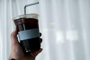 main en portant une verre de glacé café, americano dans le après midi temps photo