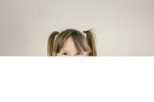 portrait de une Jeune content fille souriant derrière une blanc bannière. copie espace. photo